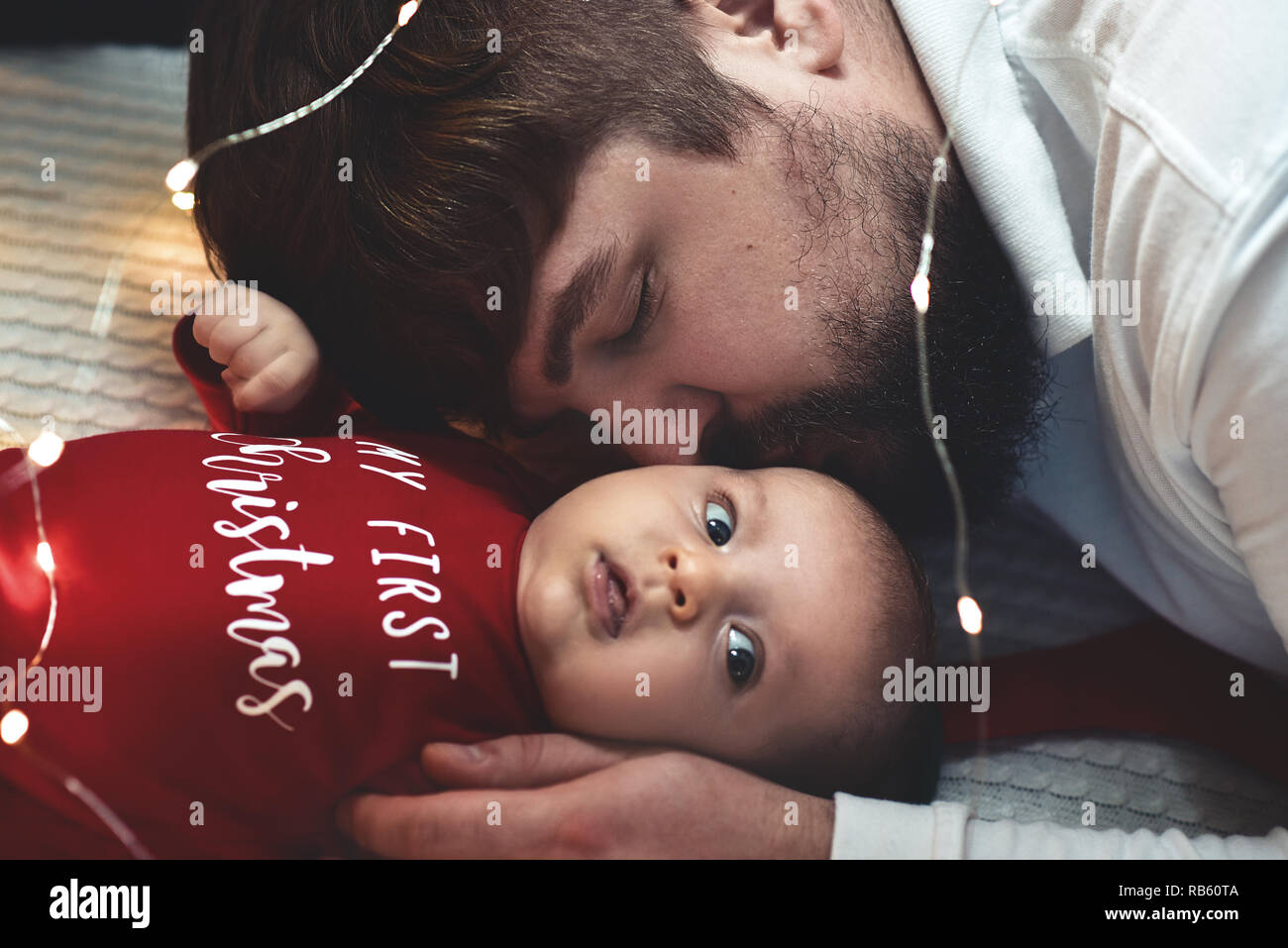 Un giovane padre bacia il suo neonato figlia. Padre e neonato closeup. Padre e il neonato sdraiato sul letto. Foto Stock