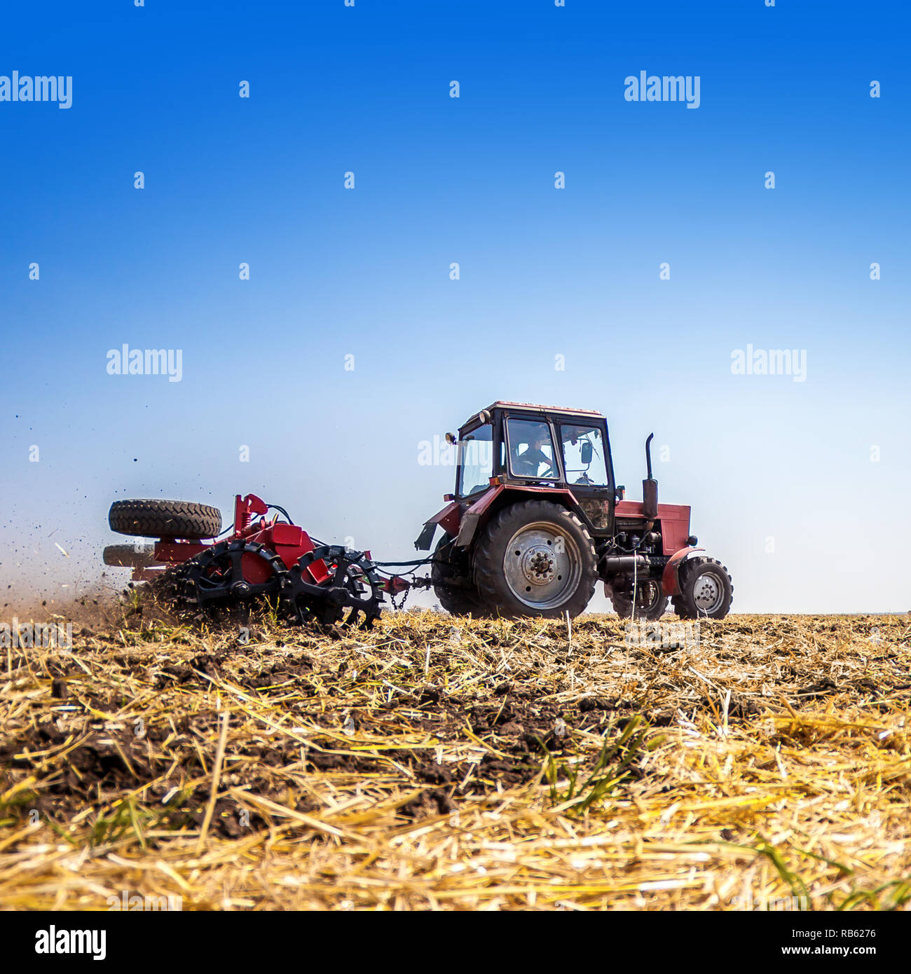 Il trattore aratri campo, coltiva il terreno per la semina di granella. Il concetto di agricoltura e macchine agricole. Foto Stock