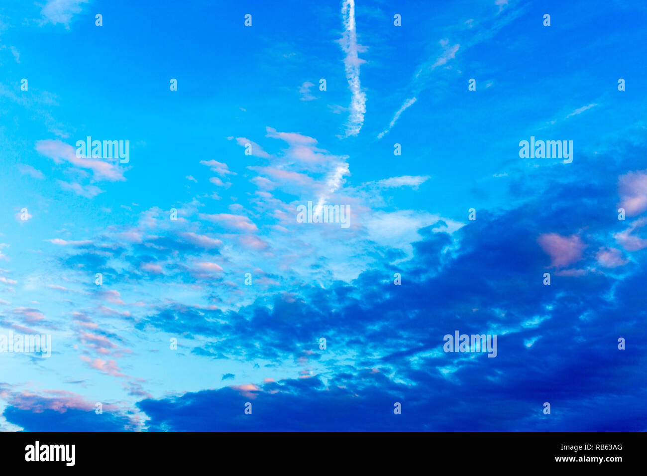 Modello di colore blu scuro, rosa e bianco delle nuvole, aereo sentieri sul cielo blu Foto Stock