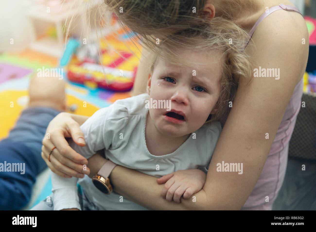 Madre consolante il suo pianto bambino a casa Foto Stock