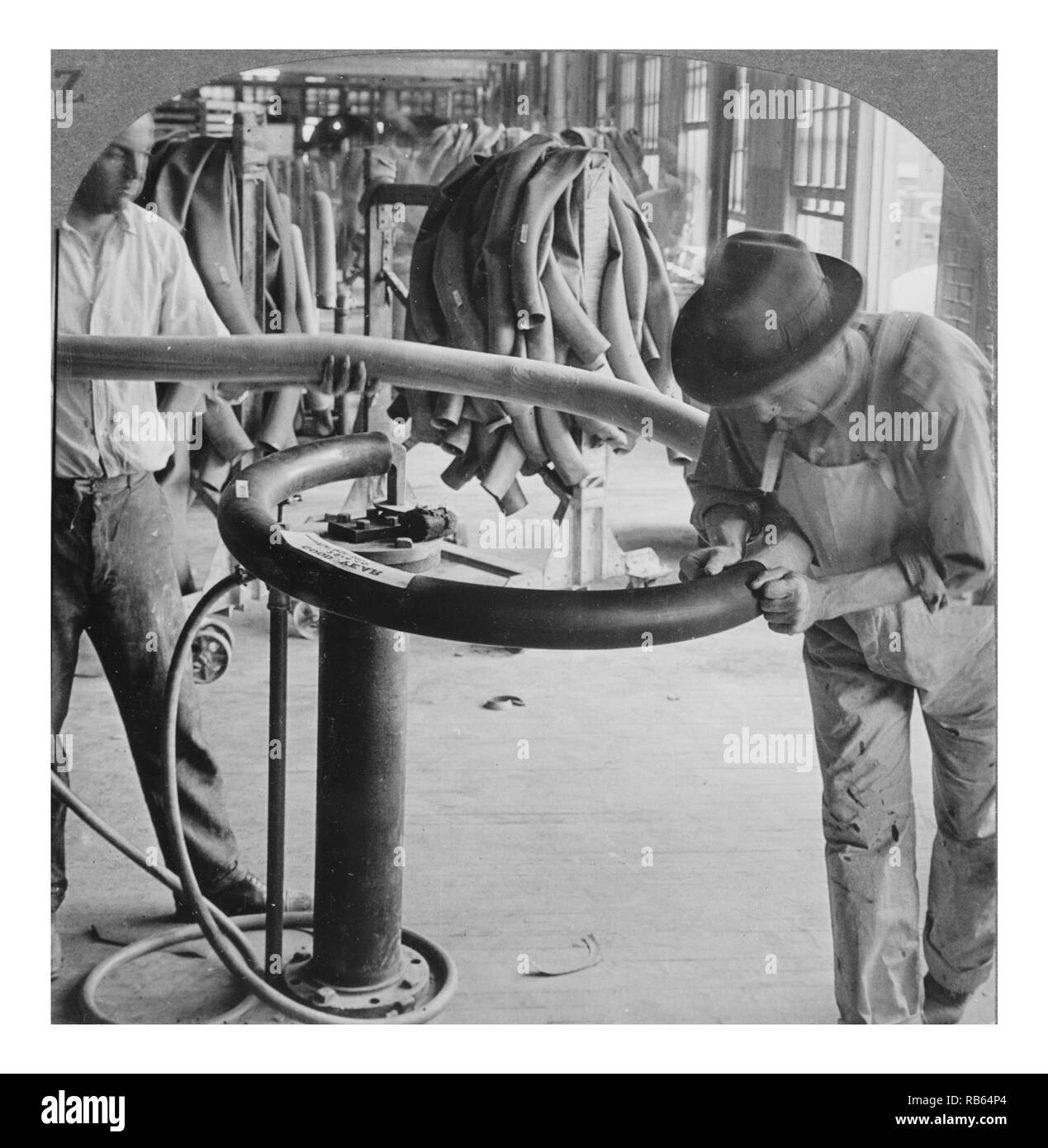 Fotografia scattata da Goodyear Tire la fabbrica dei lavoratori scomposizione di un tubo su un mandrino prima dell'invio di indurire. Datata 1928 Foto Stock