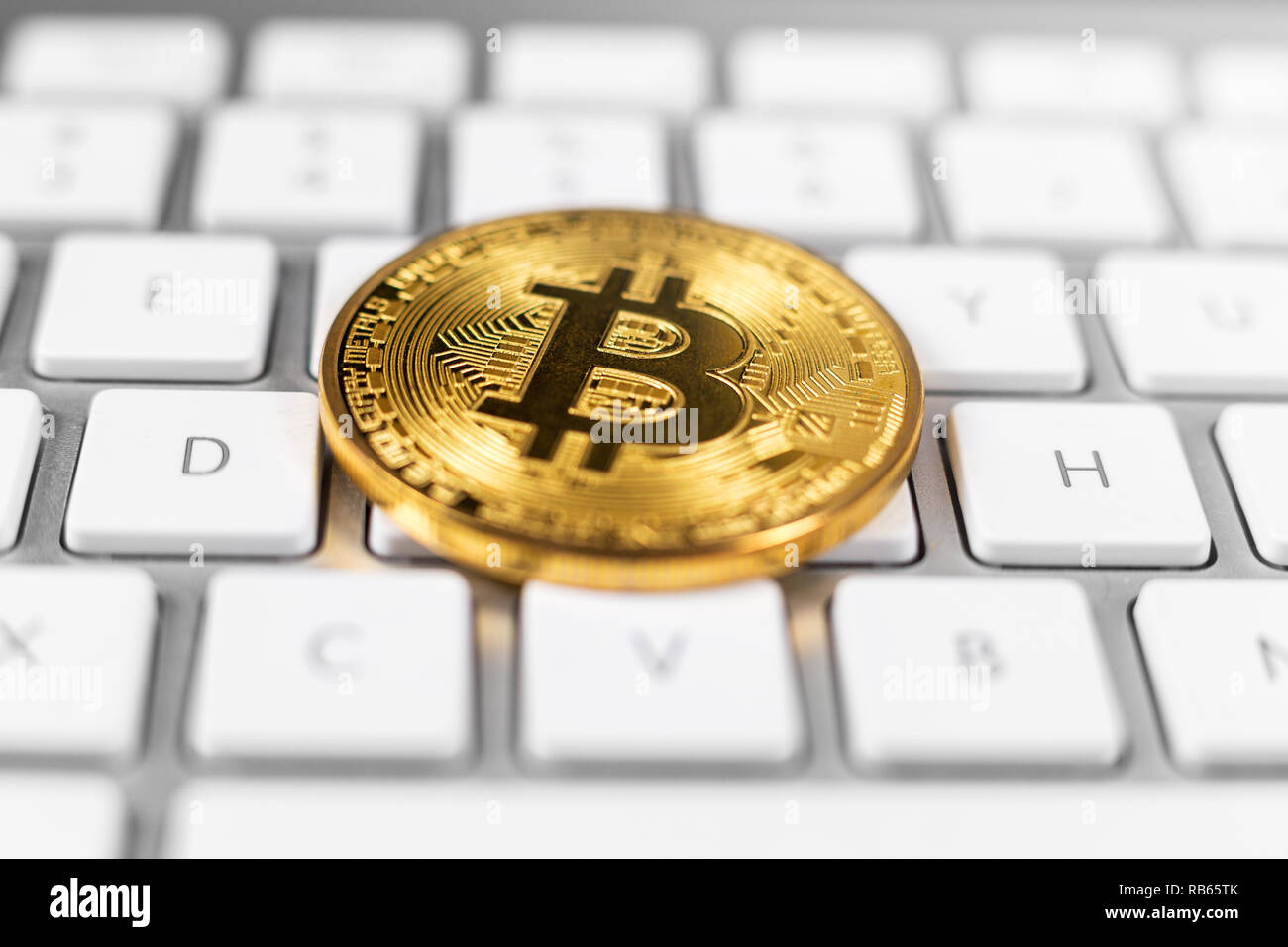 Moneta Bitcoin giacente su bianco della tastiera del computer Foto Stock