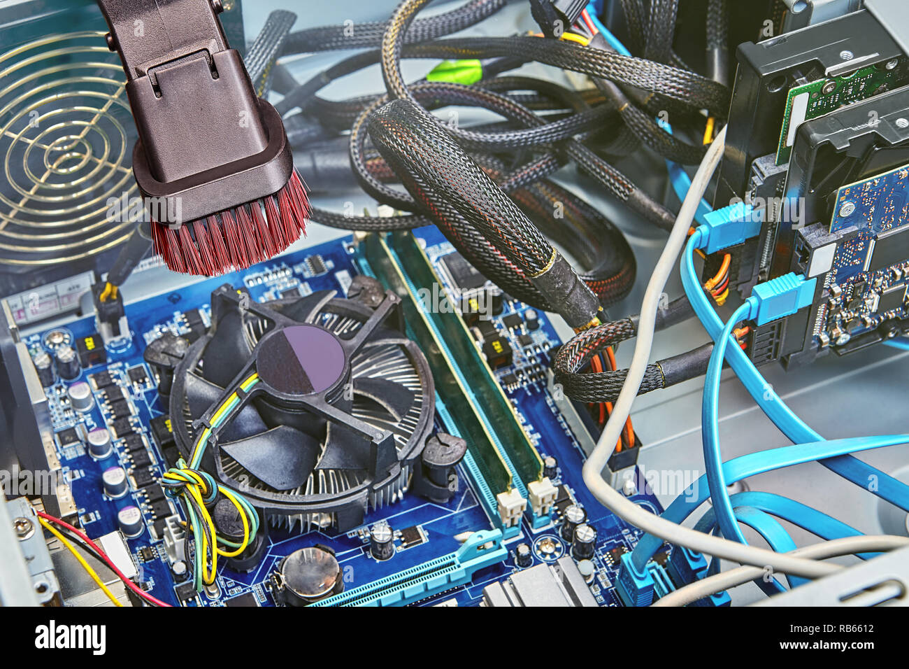 Pulizia della ventola sopra la CPU e la scheda madre interna del calcolatore Unità di sistema con l'aiuto dell'aspirabriciole. Foto Stock