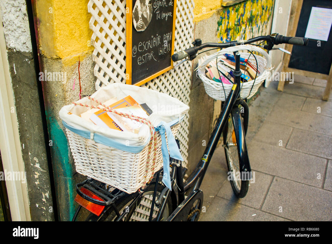 Bicicletta nero appoggiato sulla parete della strada con due cesti pieni di libri Foto Stock