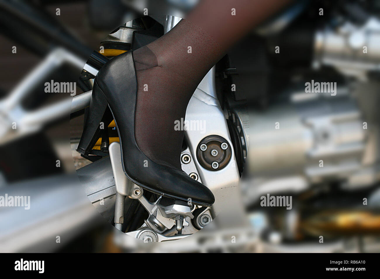 Donna bionda che indossa calza in nylon, tacchi alti e pantaloncini corti in sella a una motocicletta Foto Stock