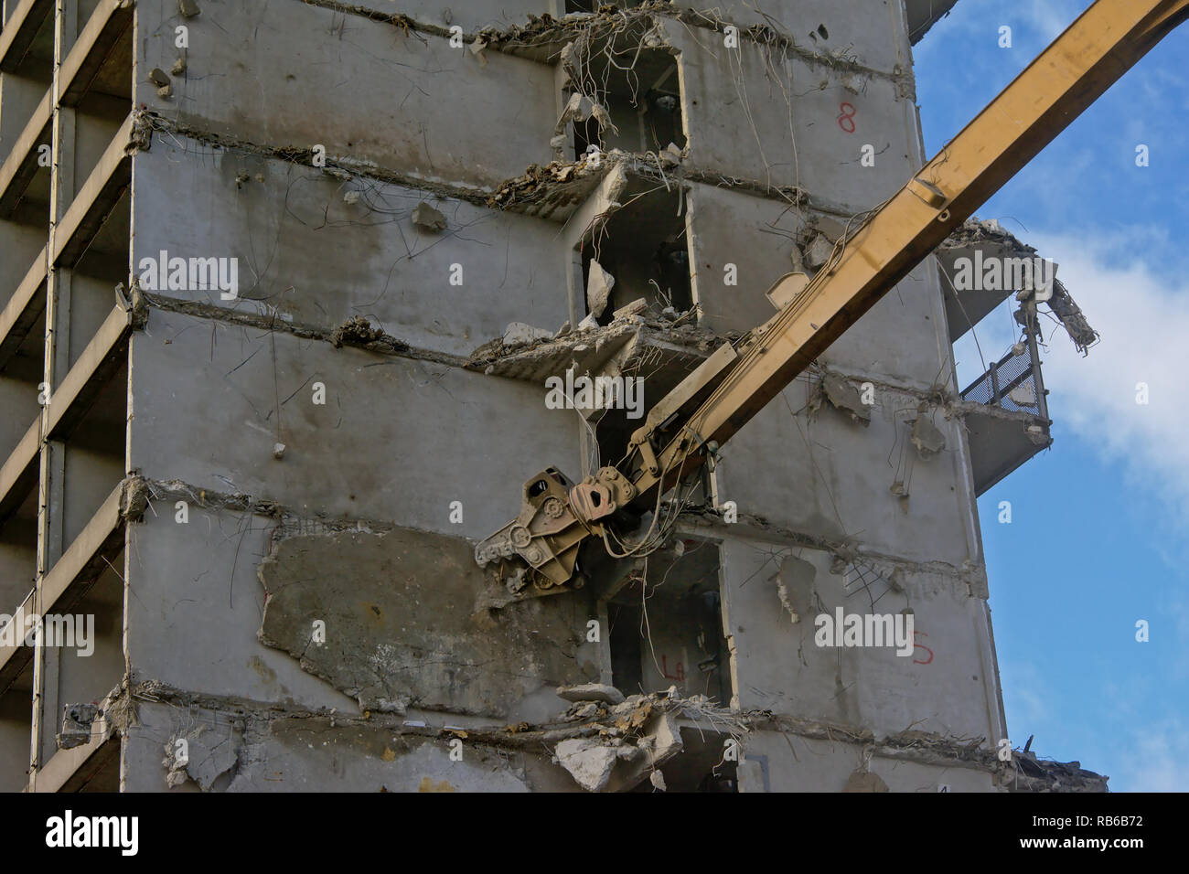 Costruzione gialla braccio gru demolendo un stripped down calcestruzzo appartamento edificio, Rabot, Gand, Belgio Foto Stock