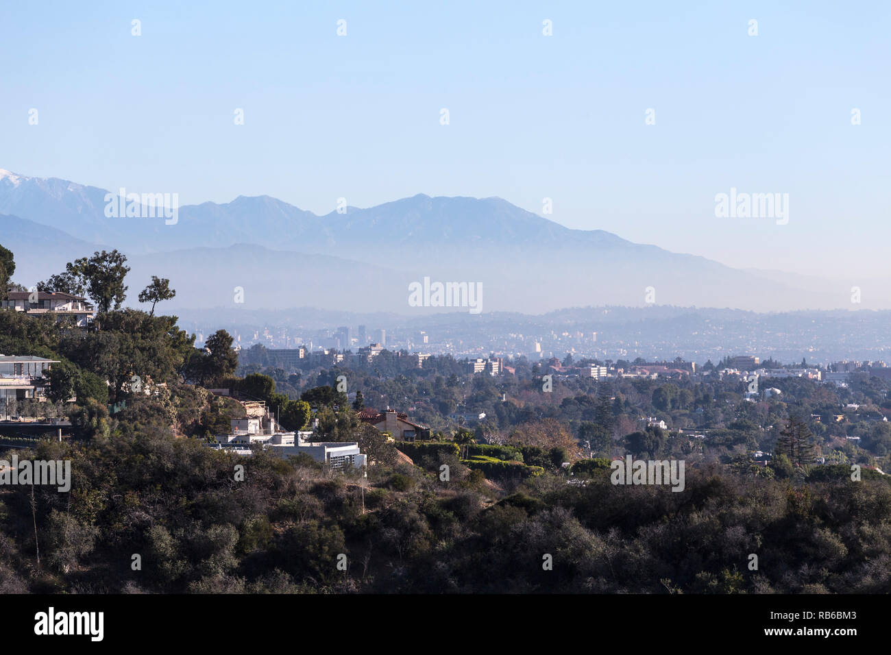 Smoggy mattina cityscape vista collina case con Hollywood e Los Angeles e le montagne di San Gabriel in background. Foto Stock