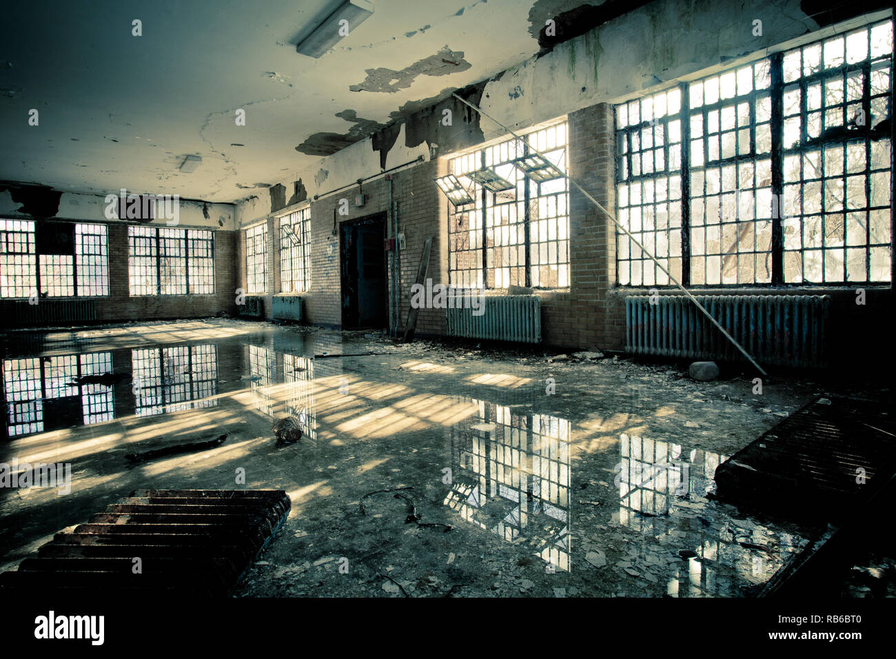 Interno di abbandonato ospedale mentale con finestre rotte e inondazioni di acqua sul pavimento Foto Stock