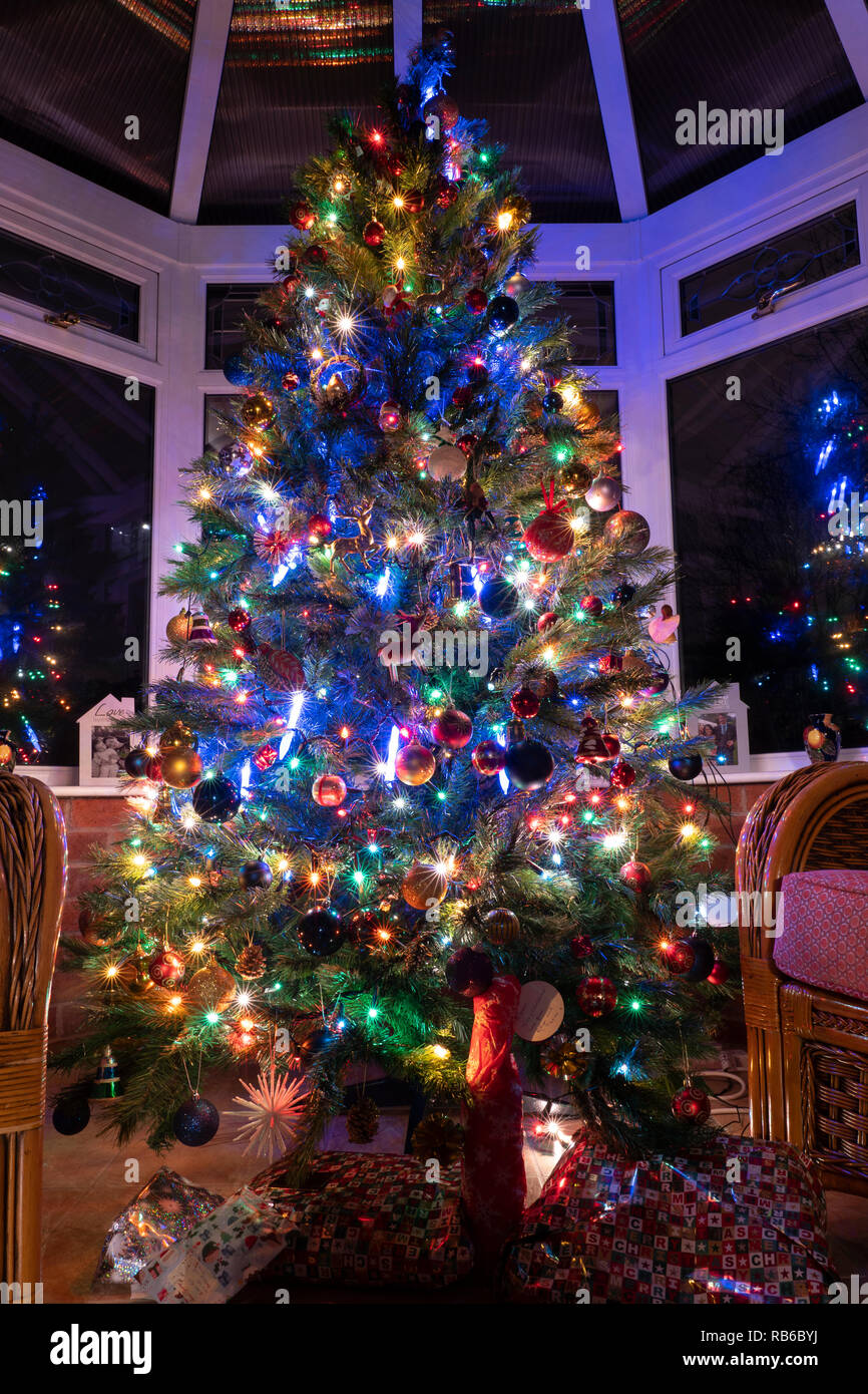 Un albero di Natale di notte in una casa veranda con presenta qui di  seguito, coperto di decorazioni e illuminato da luci fairy, REGNO UNITO  Foto stock - Alamy