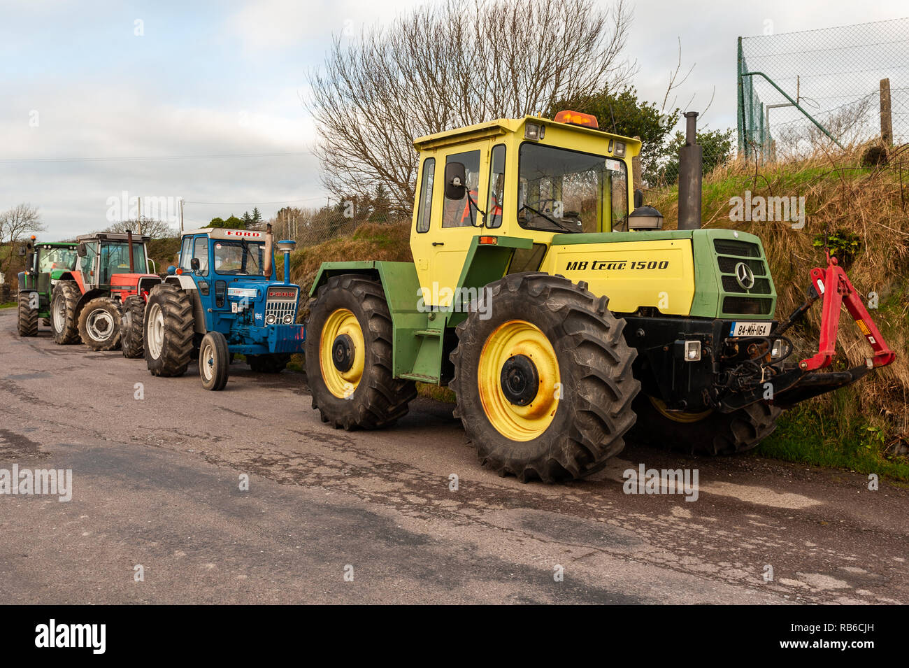 Trattori parcheggiati sul lato di una strada prima di una carità trattore eseguire in Glandore, West Cork, Irlanda. Foto Stock