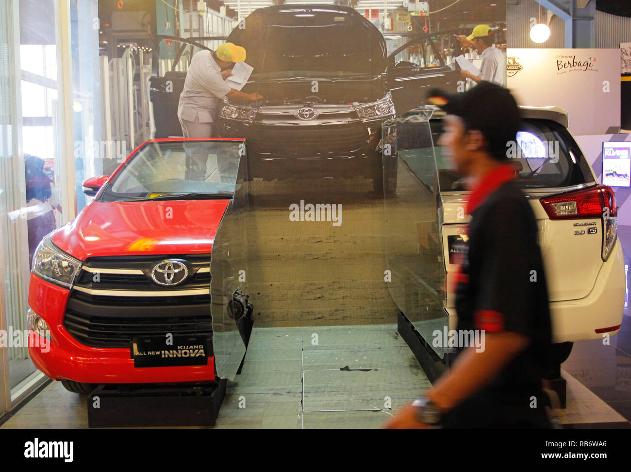 Un uomo visto accanto alla Toyota Innova auto area di raccolta dal Museo Angkut (Museo dei Trasporti). Questo museo ha migliaia di collezioni di veicoli di varie epoche. Foto Stock