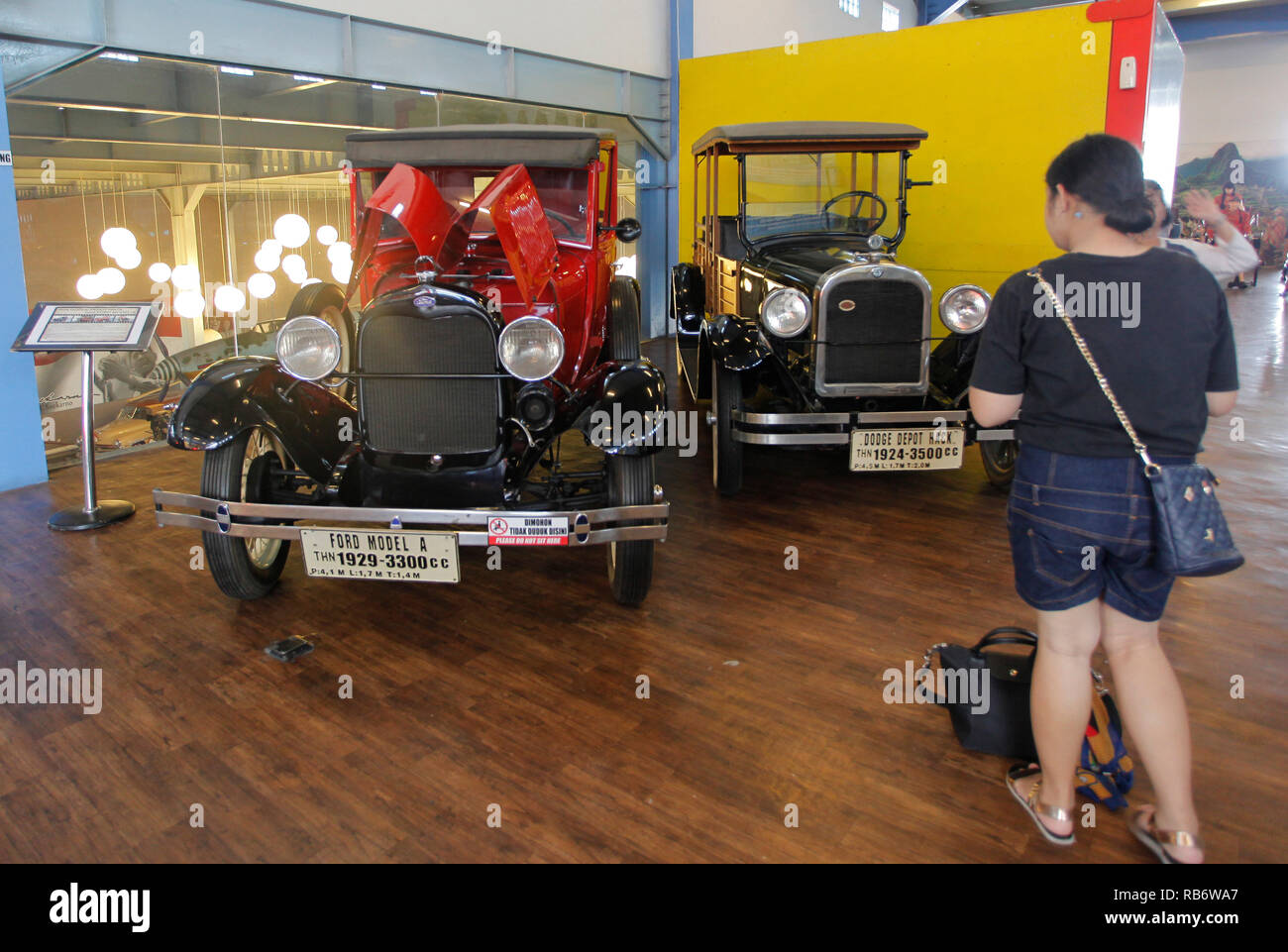 Una donna si vede guardando un vecchio Ford modello A (1929) e Dodge Depot Hack (1924) collezione di auto dal Museo Angkut (Museo dei Trasporti). Questo museo ha migliaia di collezioni di veicoli di varie epoche. Foto Stock