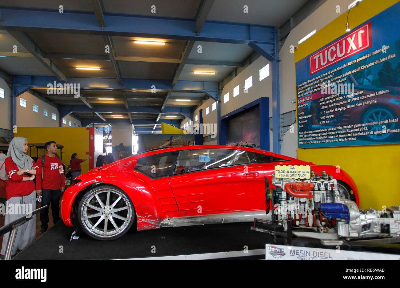 Una donna si vede osservando ??Il Tucuxi auto elettrica che è stata danneggiata da schiantarsi diversi anni fa in occasione del Angkut Museum (Museo dei Trasporti). Questo museo ha migliaia di collezioni di veicoli di varie epoche. Foto Stock