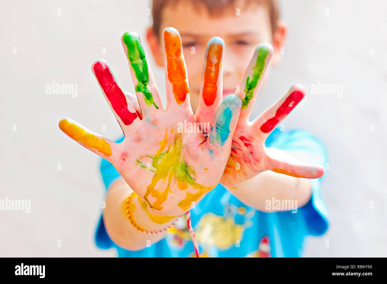 Bambino con dita dipinte in colori diversi Foto Stock