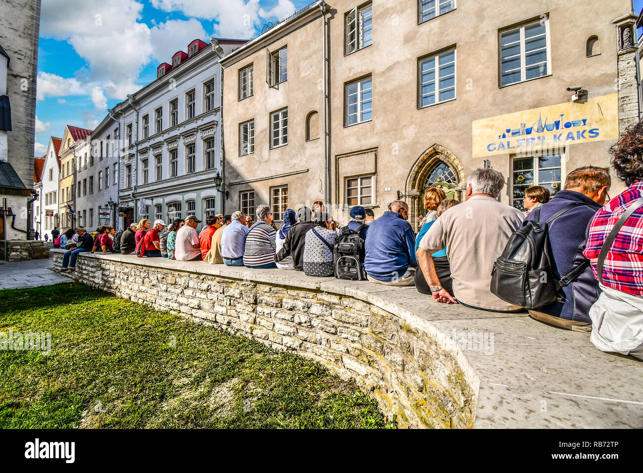 Una guida del tour e il suo gruppo di turisti sito su una parete nel centro storico della città vecchia di Tallinn, Estonia. Foto Stock