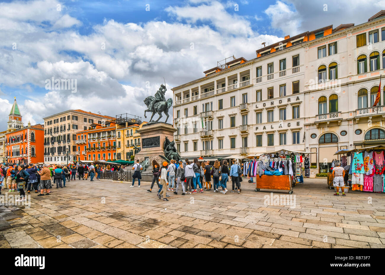 I turisti affollano le bancarelle del mercato vicino al Vittorio Emanuele statua sulla Riva degli Schiavoni sul Canal Grande vicino a Piazza San Marco Foto Stock