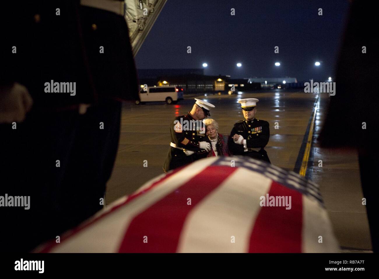 Annie Glenn orologi come Stati Uniti Marines con Marine caserma carico di Washington lo scrigno di suo marito, il Sen. John H. Glenn, Jr., su un C-130 Hercules al Wright-Patterson Air Force Base, Dayton, Ohio, a Dic. 17, 2016. Dopo aver volato 149 missioni di combattimento della Seconda Guerra Mondiale e la guerra di Corea, Glenn divenne il primo americano in orbita attorno alla terra nel 1962. Dopo essersi ritirato dal programma spaziale, Glenn era stato eletto per gli Stati Uniti Senato nel 1974 per rappresentare lo stato dell'Ohio. Foto Stock