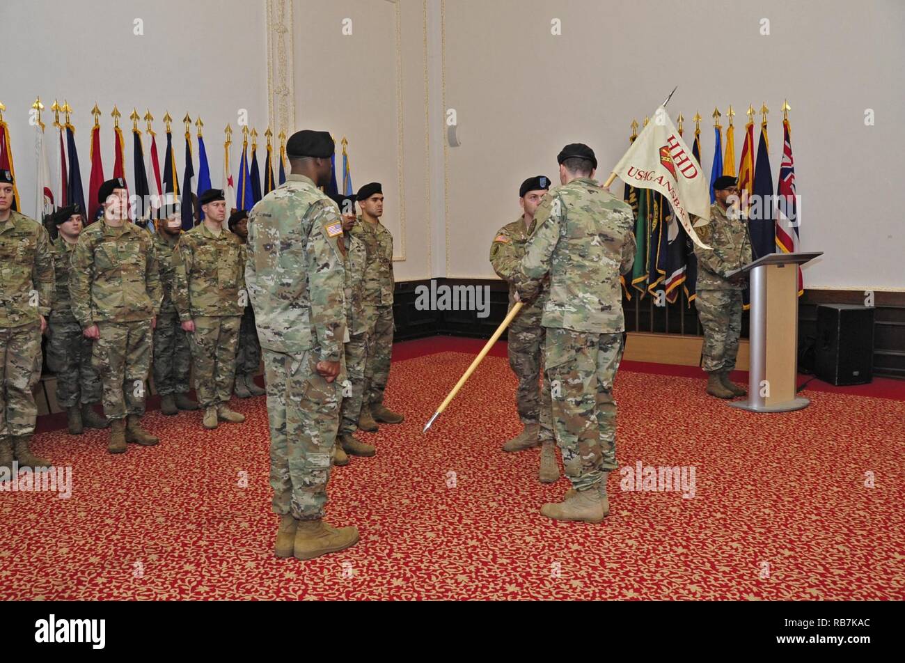 Il cap. H. Matteo Sperber, terzo da destra, comandante uscente della U.S. Presidio militare di Ansbach presso la sede centrale e la sede di distacco, passa l'unità guidon al Col. Benjamin C. Jones, USAG Ansbach commander, durante un cambio del comando cerimonia di Von Steuben centro comunitario in Ansbach, Germania, 6 dicembre 2016. In tal modo, Sperber rinunciato il comando di HHD, che è ora nelle mani di Capt. Olufemi O. Apata. Sperber aveva comandato il gruppo per due anni. Foto Stock