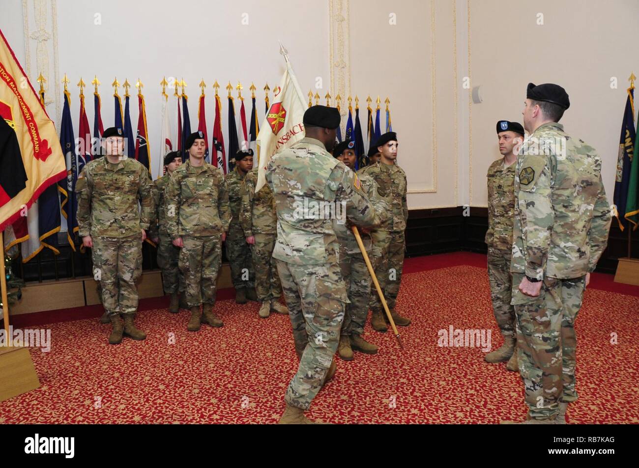 Il cap. Olufemi O. Apata, centro, comandante in entrata della sede centrale e sede di distacco, U.S. Presidio militare di Ansbach, passa la sua unità guidon torna a Sgt. 1. Classe Alvin bianco, distacco sergente, durante un cambio del comando cerimonia per l'unità 6 dicembre 2016, presso il Von Steuben centro comunitario in Ansbach, Germania. Foto Stock