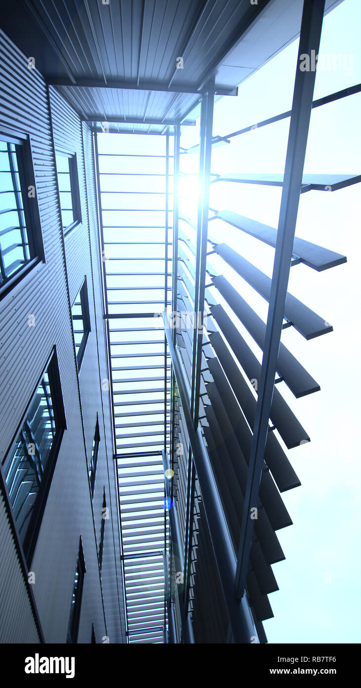 Edificio moderno di funzione esterna, girato da un angolo basso con windows che riflette la lunga stecche per il valore estetico e uso creativo della luce. Foto Stock