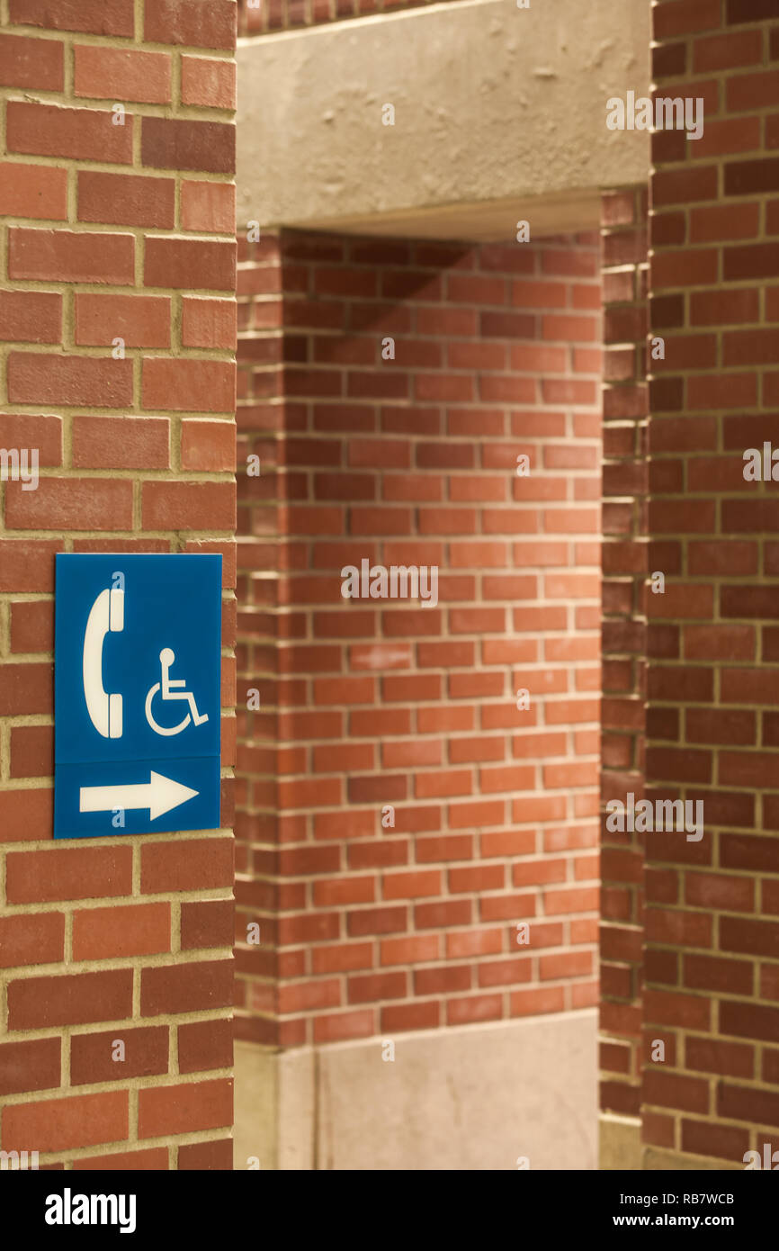 Persona disabile del cartello informativo su un rosso muro di mattoni Foto Stock