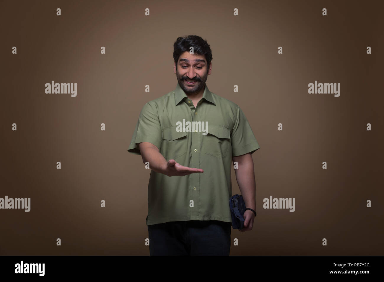 Uomo con una piccola borsa in una mano e guardando il suo palm a sorpresa. Foto Stock