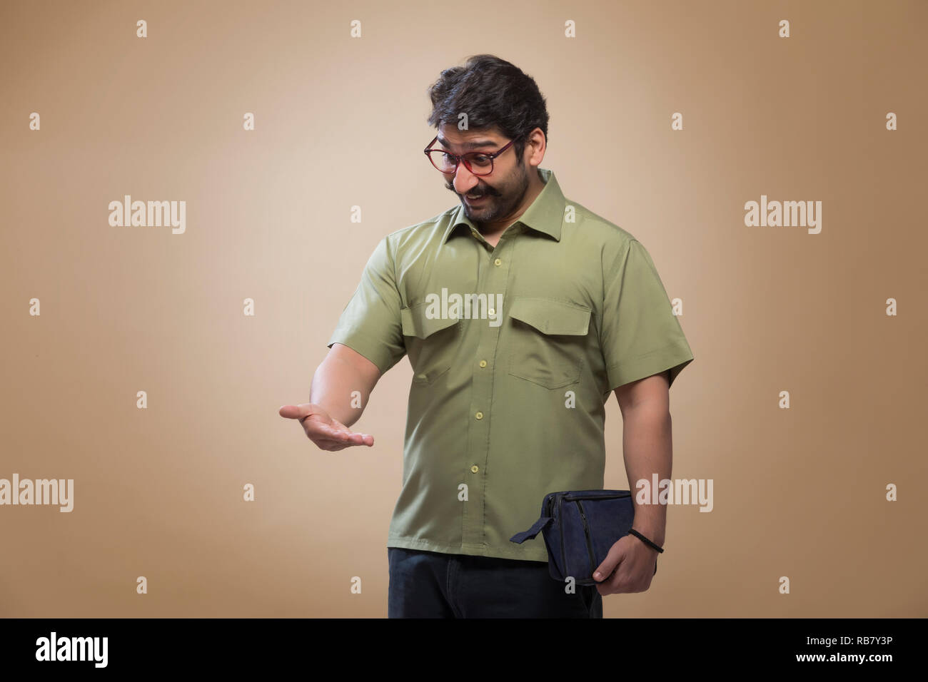 Uomo che indossa occhiali tenendo un piccolo sacchetto in una mano e guardando il suo palm a sorpresa. Foto Stock