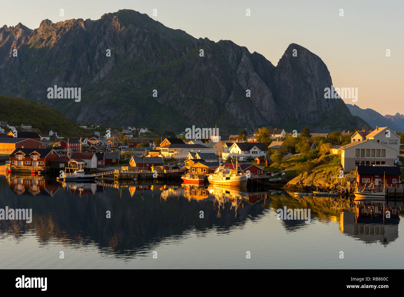 Vista del villaggio di Reine su Moskenesøya, le isole Lofoten in Norvegia, l'Europa. Case al mare sono illuminate dal sole di mezzanotte durante la sera tardi. Foto Stock