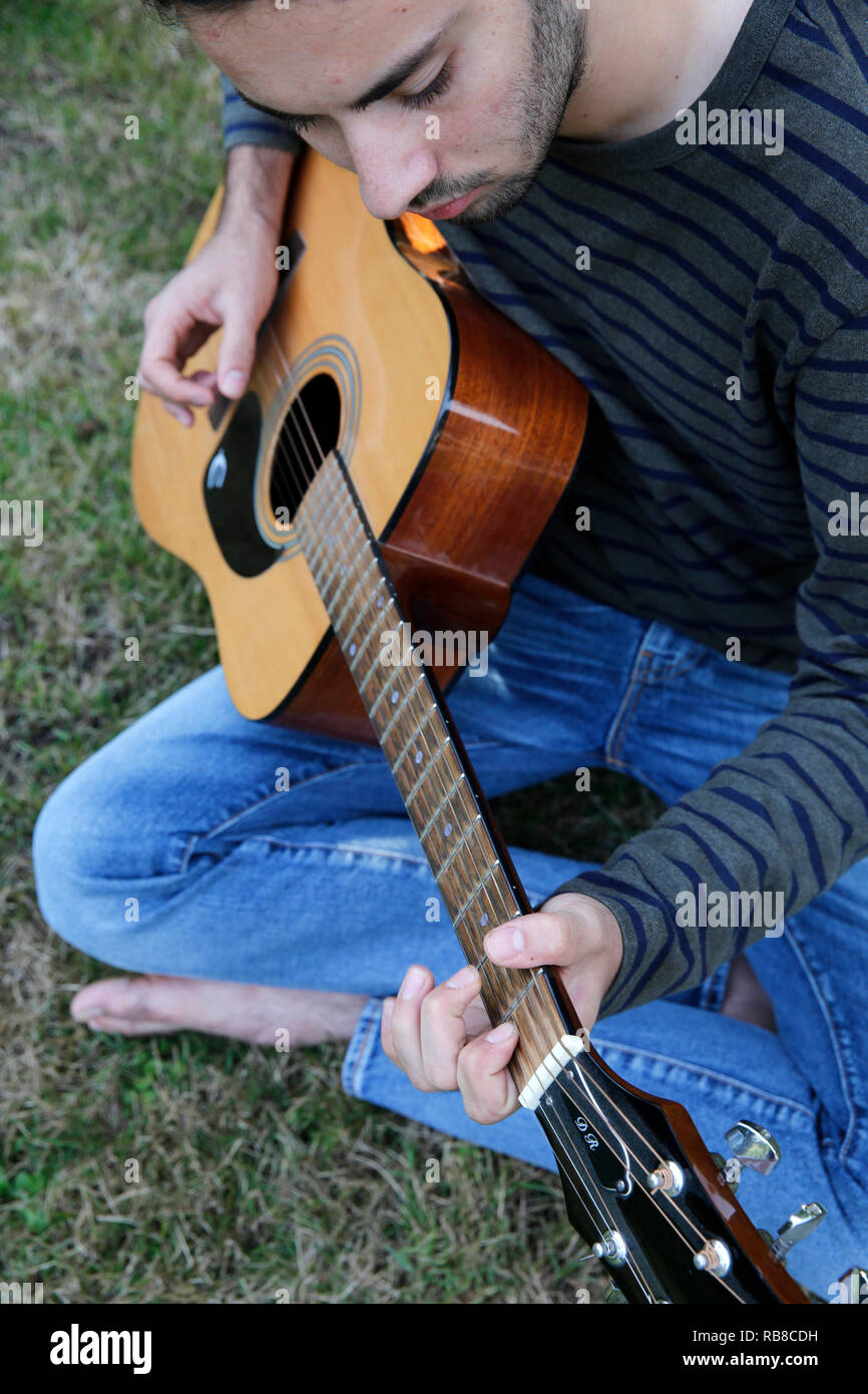 Giovane uomo di suonare una chitarra in un giardino. La Francia. Foto Stock