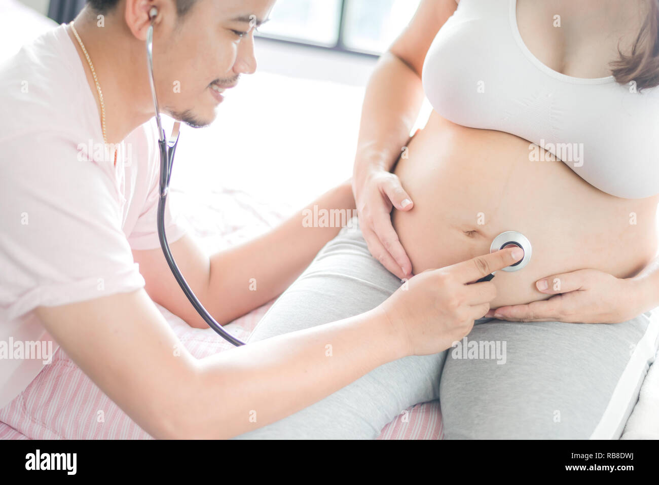 Asian donna incinta con grande pancia. Rilassarsi a casa con il marito. Foto Stock