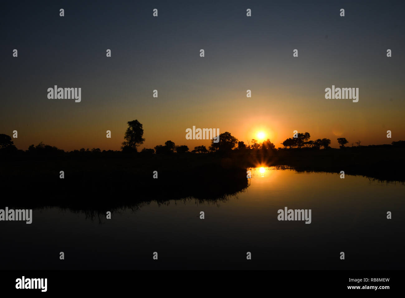 Bel tramonto mentre sulle rive di un fiume safari nel delta dell'Okavango in Botswana Foto Stock