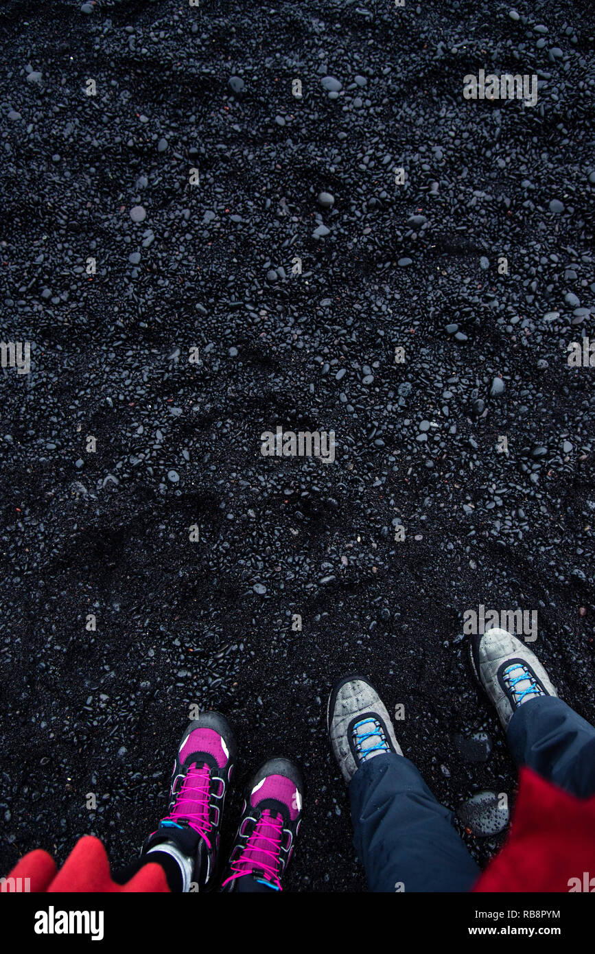Matura in piedi sulla sabbia nera spiaggia Reynisfjara in Islanda pov Foto Stock