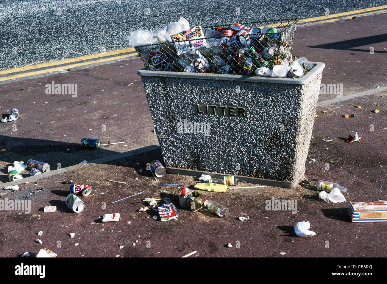 Un contenitore di rifiuti oltre-fluente di spazzatura.spazzatura sul marciapiede e la strada.una scena in un resort per vacanze sulla costa ovest dell'Inghilterra. Foto Stock