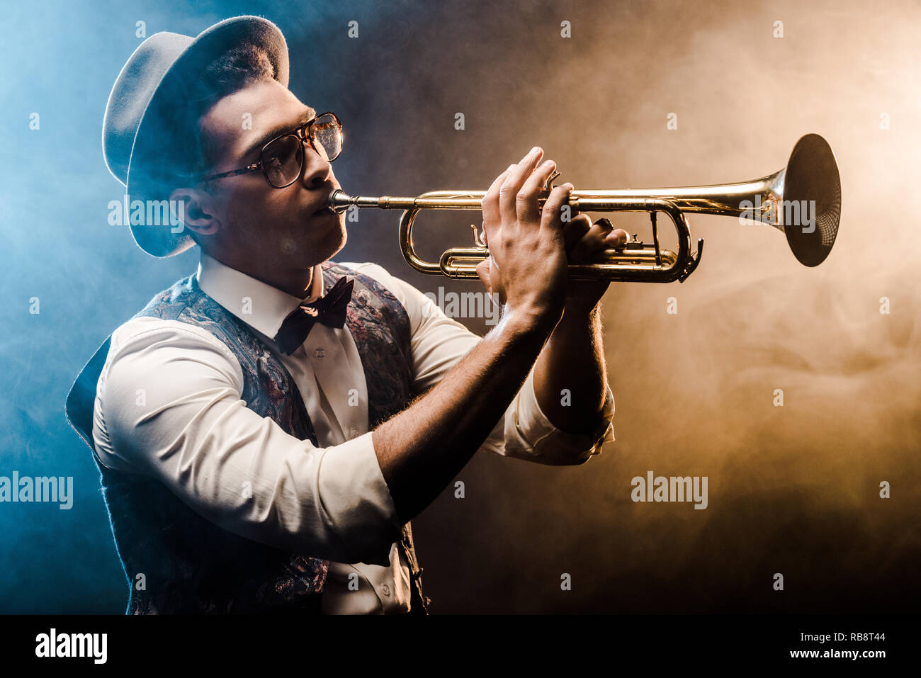 Giovane jazzista giocando sul riduttore laterale sul palco con illuminazione drammatica e di fumo Foto Stock