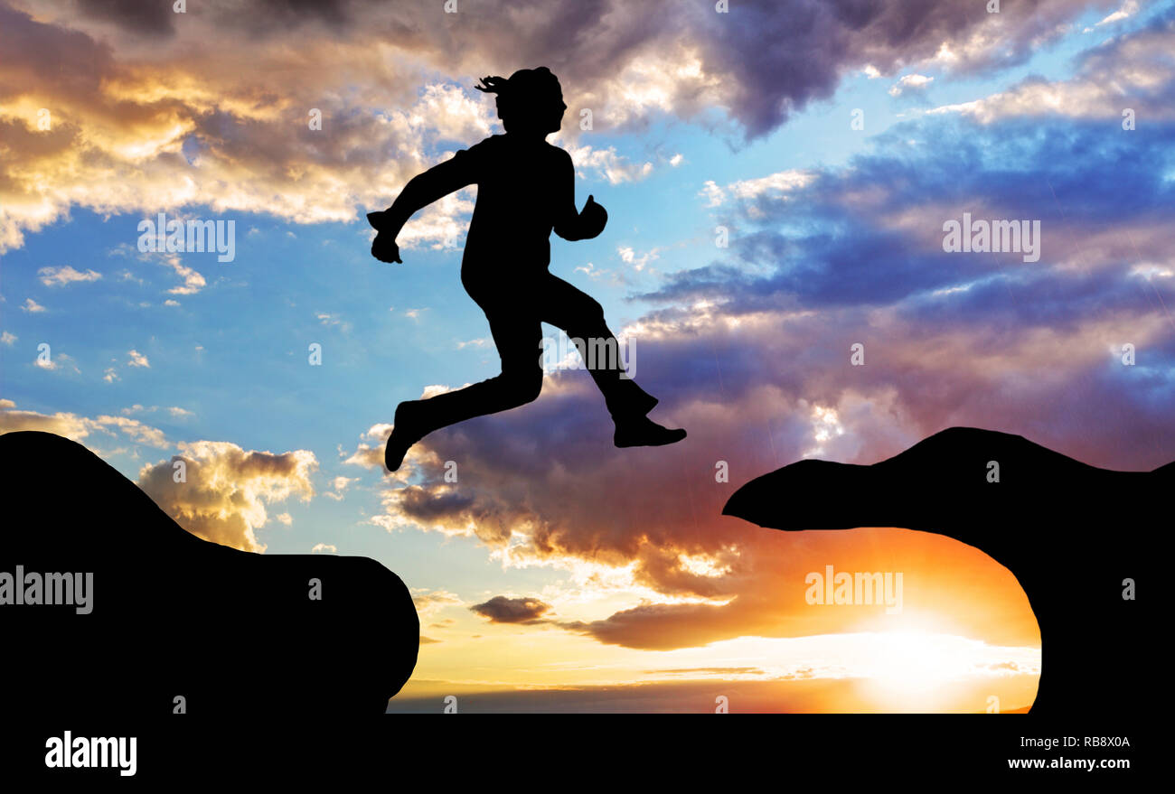 Donna salto oltre i canyon presso un tramonto Foto Stock