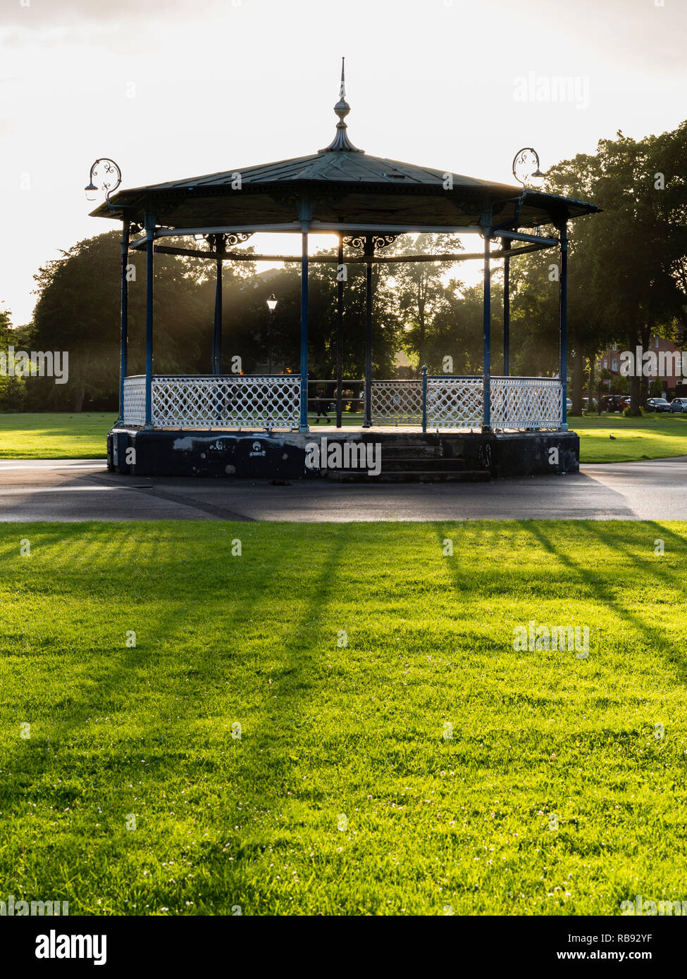 Il Victorian bandstand nel Royal Pump Room giardini, Leamington Spa, Regno Unito Inghilterra, con sole basso dietro la colata lunghe ombre. Foto Stock