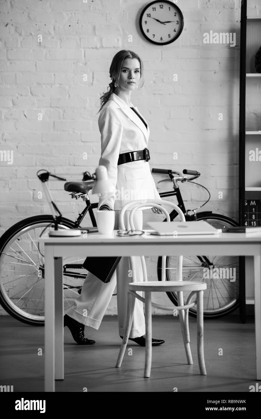 Foto in bianco e nero di imprenditrice in abbigliamento formale in un ufficio moderno interno Foto Stock
