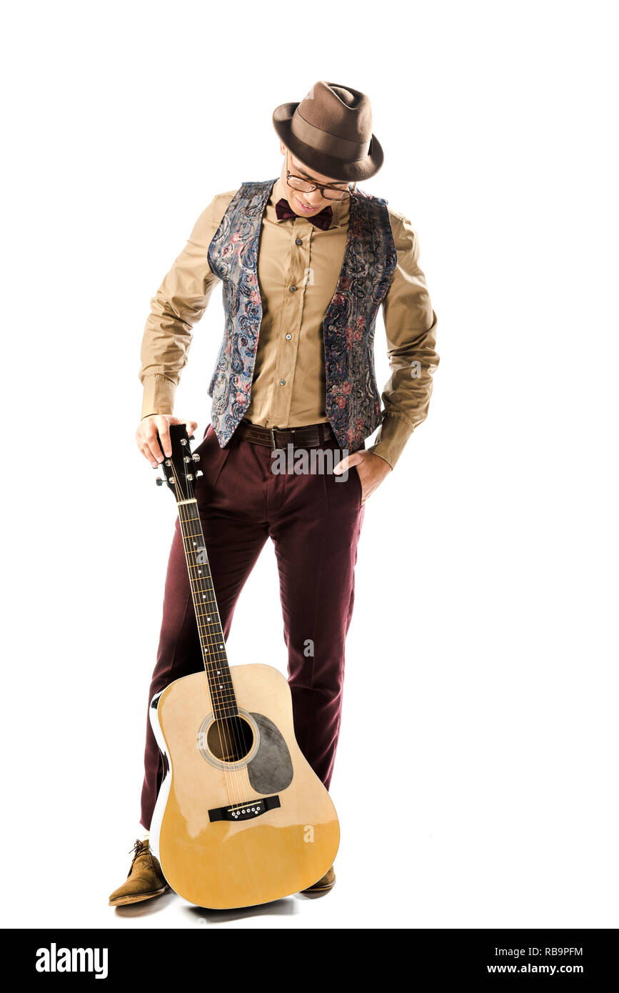 Musicista maschio nel cappello e occhiali in posa con la chitarra acustica isolato su bianco Foto Stock
