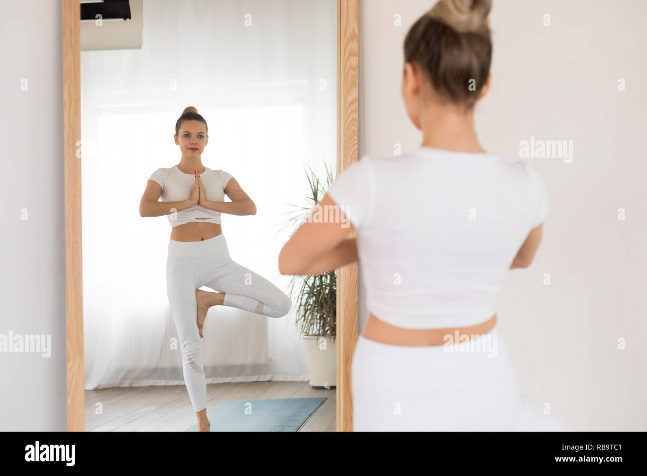 Sport giovane donna fare yoga davanti allo specchio a casa. Foto Stock