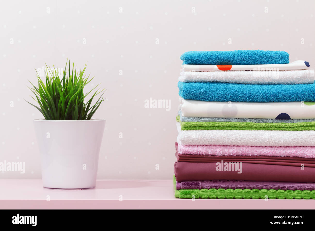Sul comò vi è una pila di pulire stirare la biancheria da letto e da bagno, piegato multi-colore di asciugamani e un impianto di home stand. Foto Stock