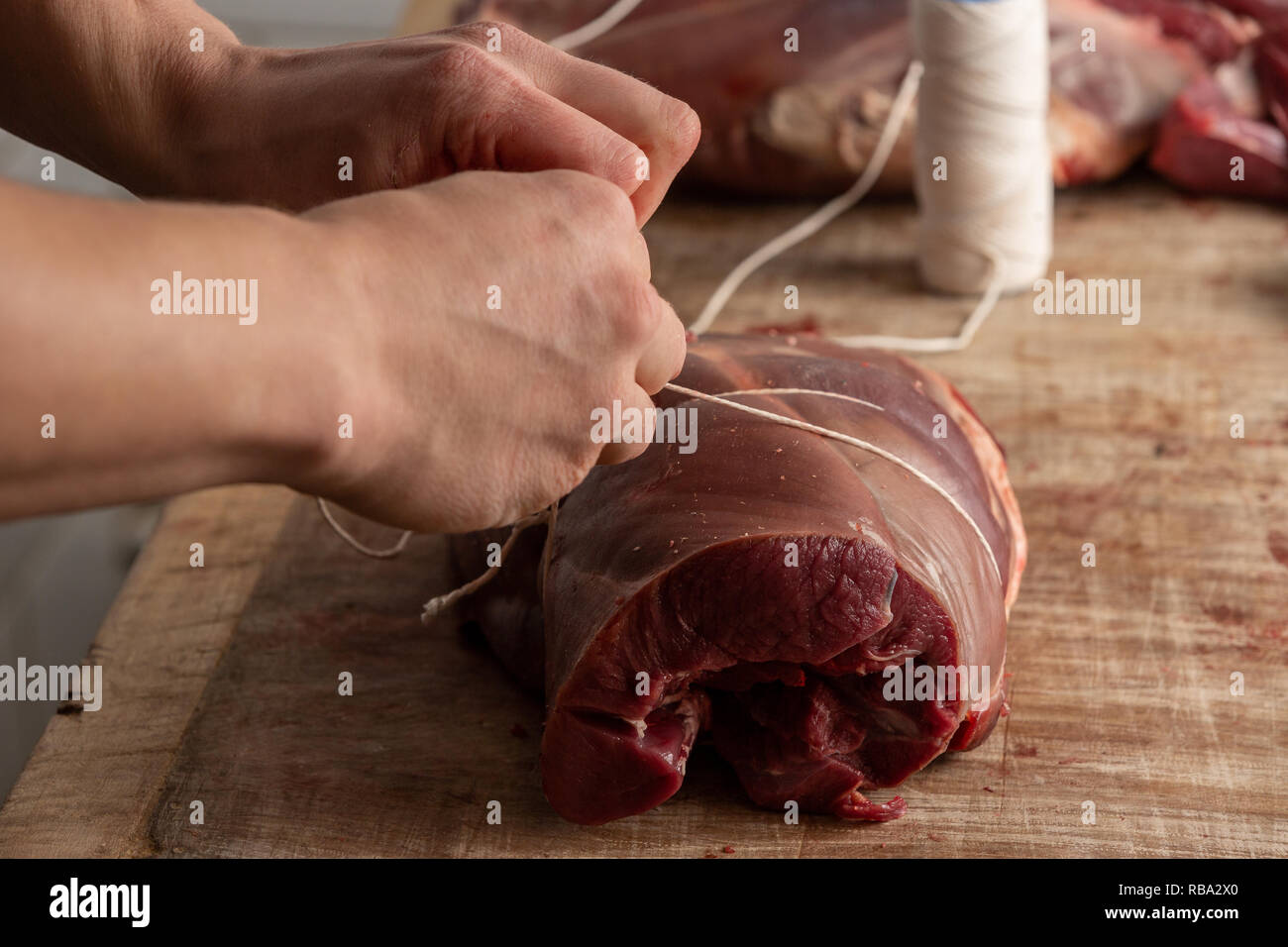 Butcher prepara la carne di cervo a Gog Farm Shop, Stapleford, Cambridge, Cambridgeshire Foto Stock