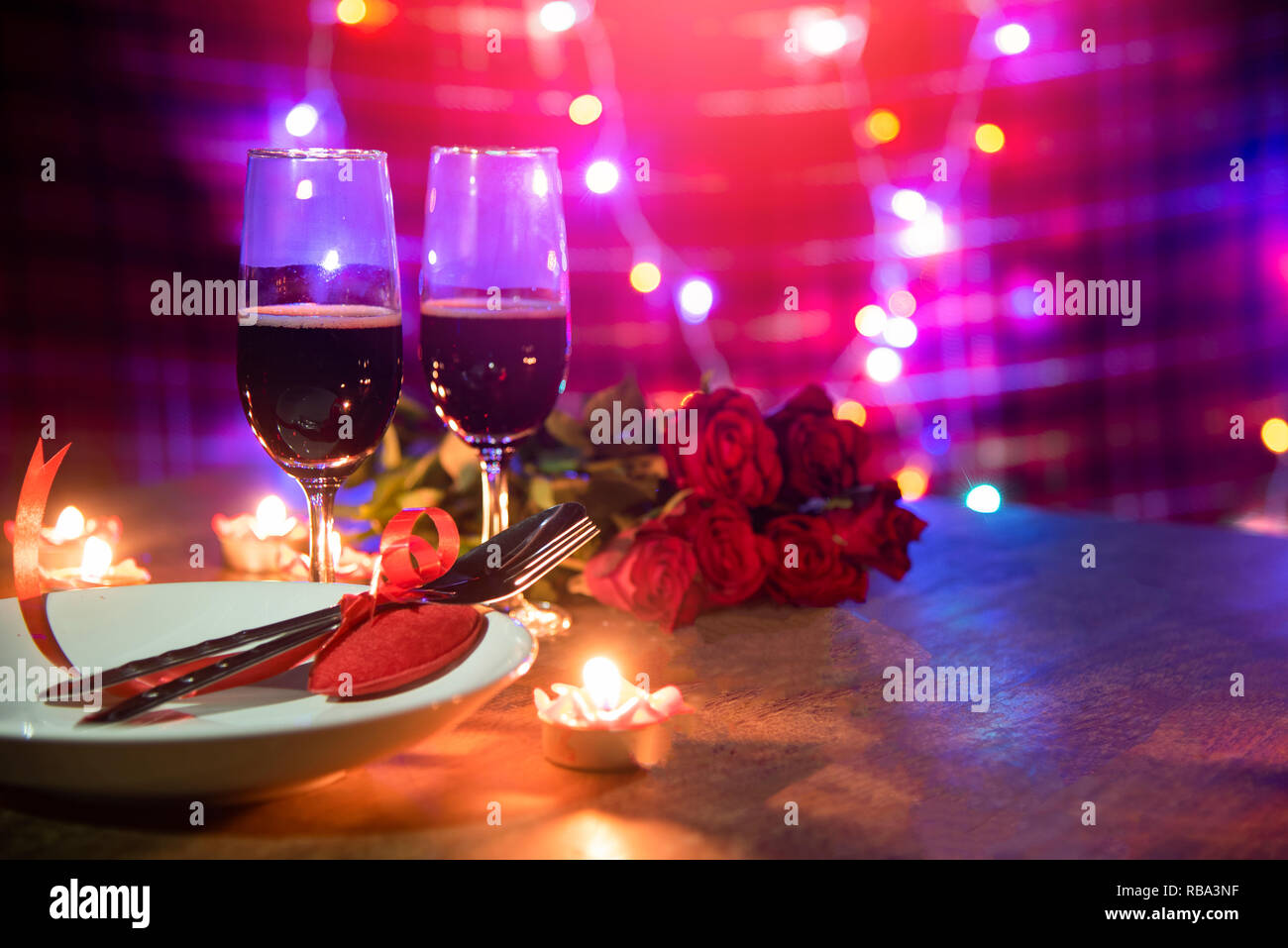 Valentines dinner romantic love concept / Romantic table setting decorated with Red heart fork spoon on plate and couple champagne glass wine roses wi Foto Stock