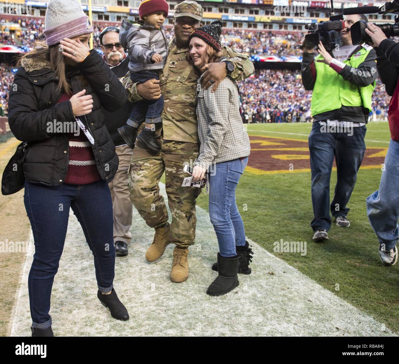 Jessica L. Watkins (sinistra) pulisce le lacrime come suo marito Spc. Leo Watkins Jr., U.S. La riserva di esercito di polizia militare soldato con la 372 Polizia Militare Società in Cumberland, Maryland, tiene il suo figlio più giovane durante una sorpresa homecoming durante il Washington Redskins partita contro New York Giants a FedEx in campo Landover, Maryland, 1 gennaio. Il Martinsburg, West Virginia native ha trascorso gli ultimi dieci mesi a Guantanamo Base Navale, Cuba. ( Foto Stock