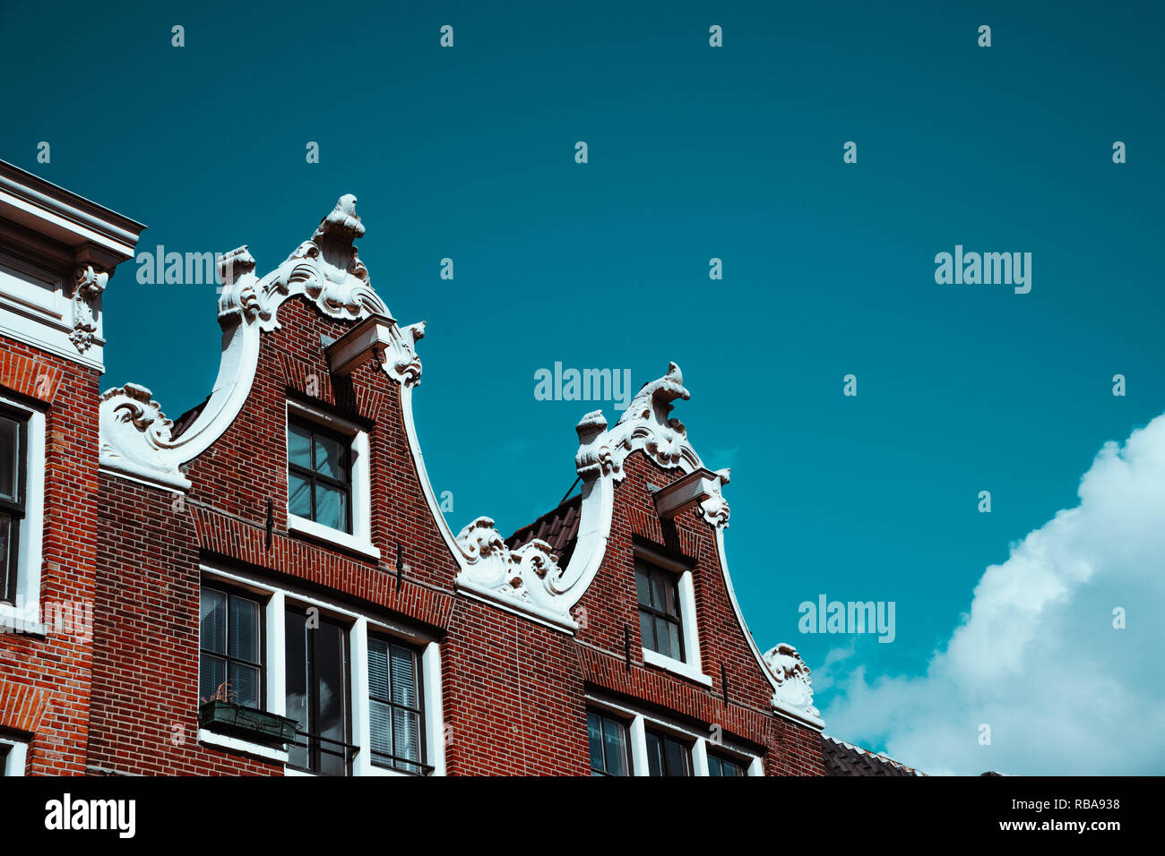 Close-up della vecchia facciata di edificio e la decorazione del tetto contro il cielo blu in Amsterdam. I dettagli architettonici nord dei Paesi Bassi Foto Stock