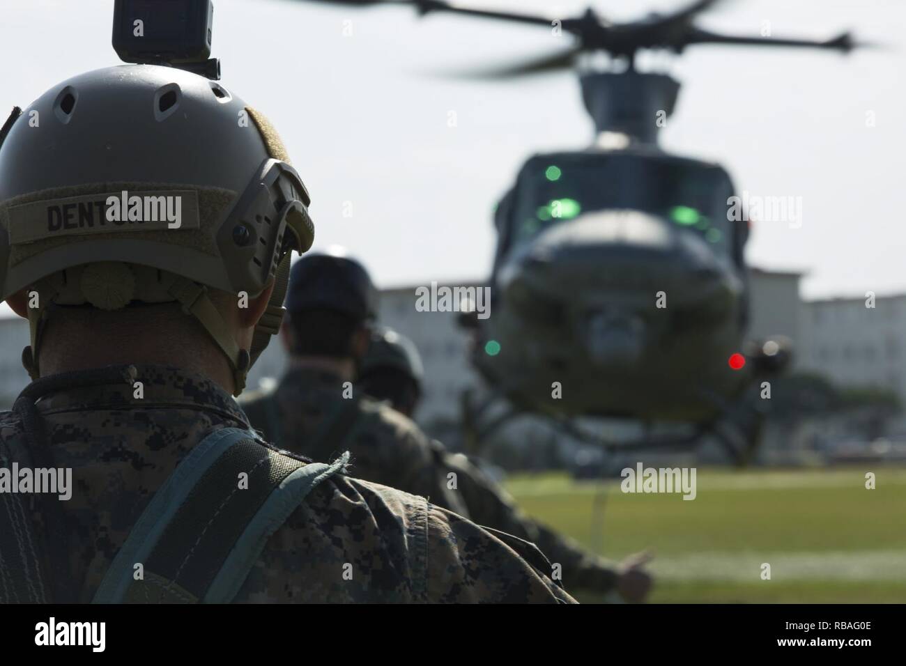Stati Uniti Marine Il Mag. Cody W. Denton osserva la UH-1Y Venom prendono il volo durante la pattuglia speciali di inserimento ed estrazione in elicottero e fune di sospensione di formazione tecnica su Camp Hansen, Okinawa, in Giappone, Dic 18, 2018. SPIE rigging, fast roping e rappelling Marines permettono di entrare e uscire da zone di sbarco che sono troppo pericolose per gli elicotteri a terra in modo sicuro. SPIE e corsi di formazione sulle risorse umane nella scienza e nella tecnica di insegnare Marines nodo appropriato e rappelling tecniche, e costruisce la fiducia in manovra da aeromobili a terra. Denton, un nativo di Sant'Elena, California, è un assalto anfibio veicolo ufficiale con Expeditionary Foto Stock