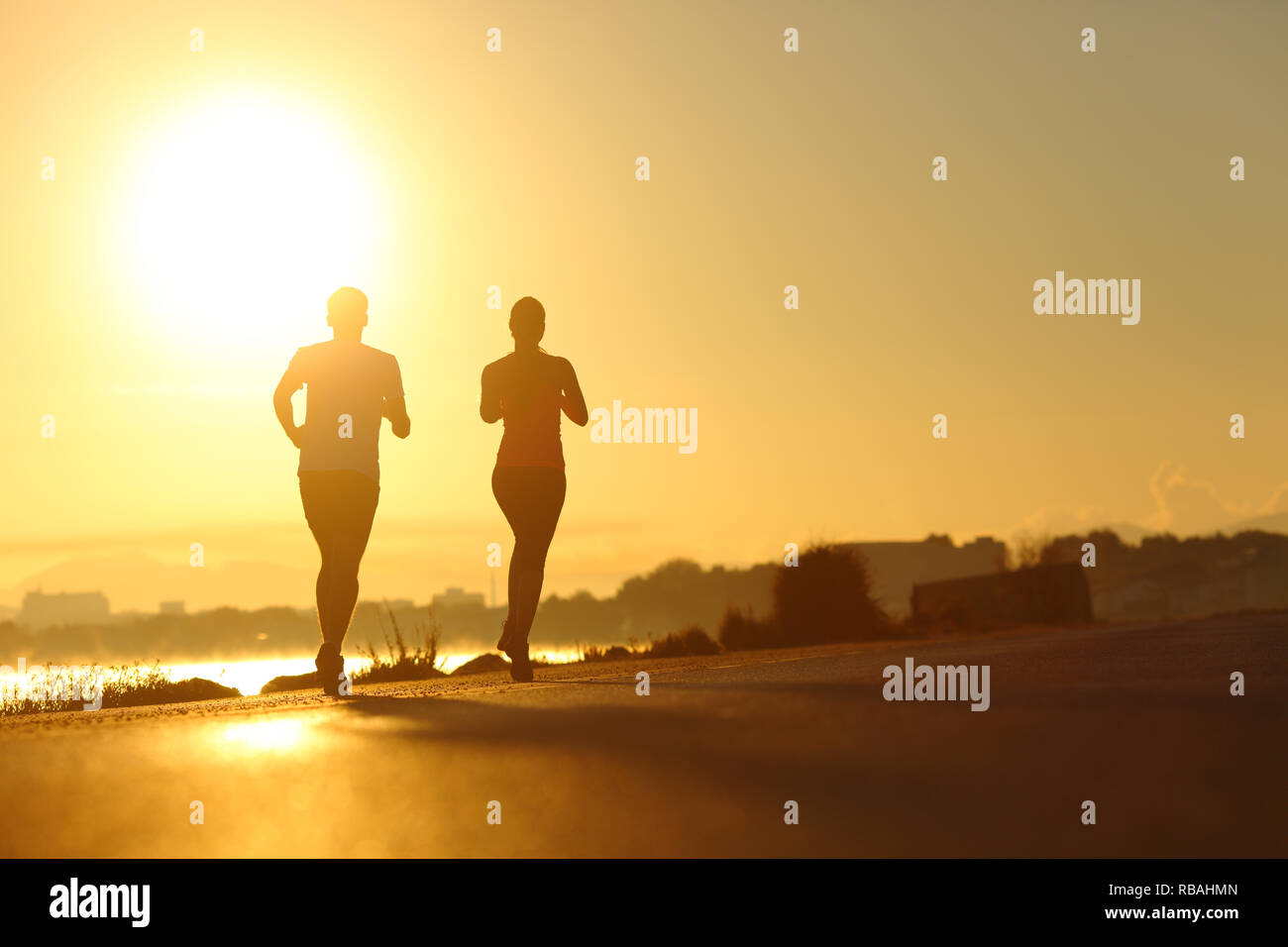 Silhouette di un paio di praticare lo sport in esecuzione al tramonto sulla strada Foto Stock