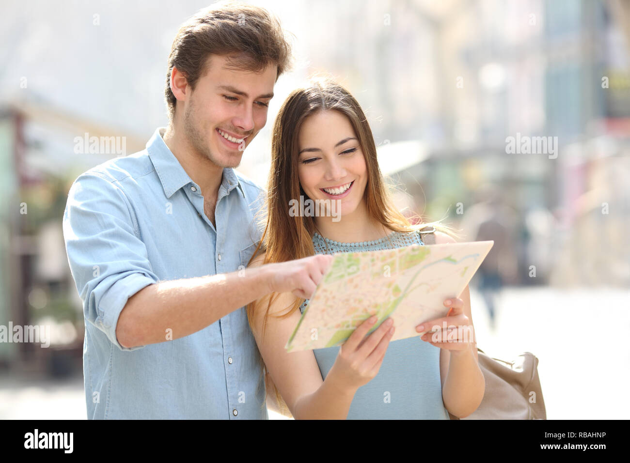 Felice coppia controllo mappa su carta in vacanza in piedi in una grande città street Foto Stock