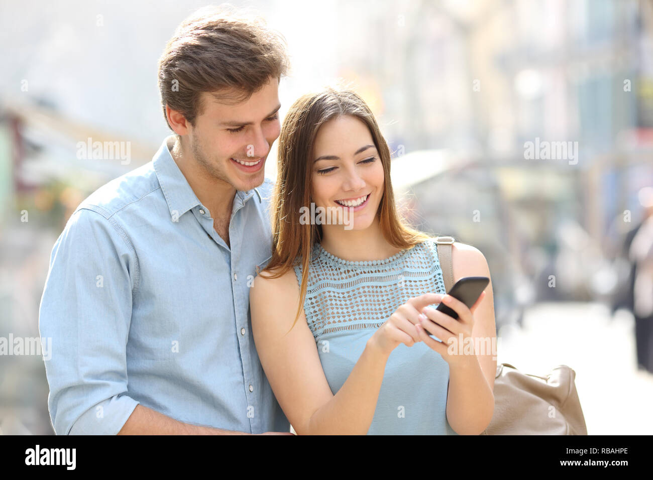Coppia felice a piedi in strada il controllo smart del contenuto del telefono Foto Stock