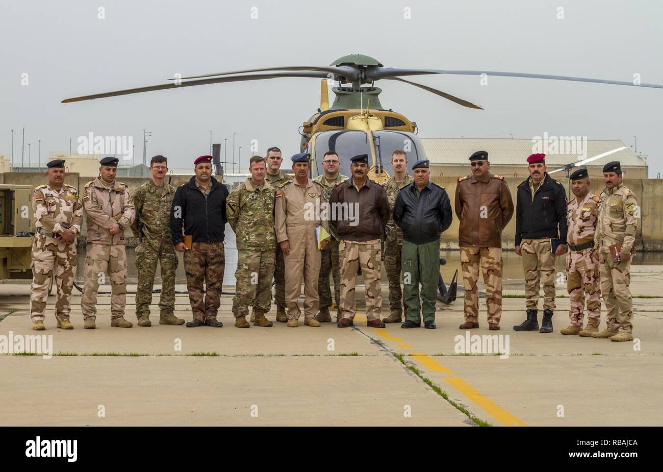 Illustri visitatori compreso di USA e soldati iracheni e gli avieri posano per una foto dopo un tour di attività dell'aviazione e le funzionalità di un breve dell'esercito iracheno Aviation Team presso il Camp Taji, Iraq, Dic 20, 2018. La Coalizione Aviation consulenza e formazione del team si alzò in piedi nel febbraio 2018 per migliorare l'ISF dell'aviazione con capacità di formazione condotta a Taji. Foto Stock
