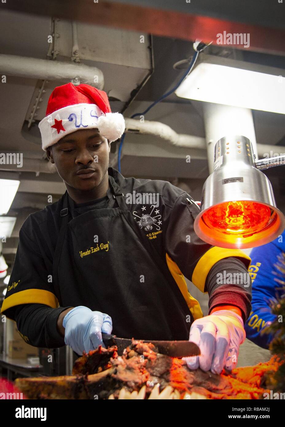 NORFOLK, Virginia (dec. n. 25, 2018) specialista culinaria marinaio Amari Drummond, da Atlanta, scolpisce un arrosto di manzo durante un giorno di Natale pasto servito a bordo della energia nucleare portaerei USS Dwight D. Eisenhower (CVN69).Ike sta subendo una prevista disponibilità incrementale (PIA) durante la fase di manutenzione della flotta ottimizzato il piano di risposta (OFRP). Foto Stock